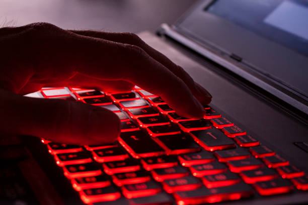 istock Close up of fingers typing on glowing red backlight keys on a computer keyboard. in the dark. Computer hacker, internet fraud or spying concept. 1176284734