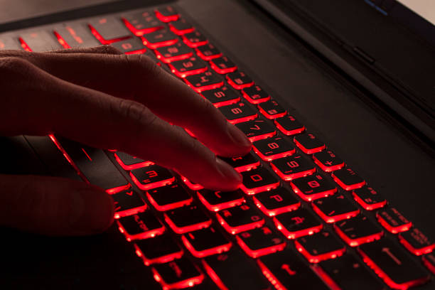 istock Close up of fingers typing on glowing red backlight keys on a computer keyboard. in the dark. Computer hacker, internet fraud or spying concept. 1176284767