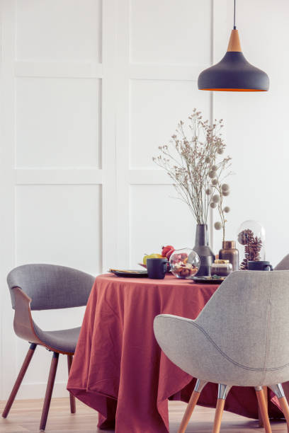 istock Elegant dining room table covered with ginger tablecloth in bright living room interior with stylish chairs 1176286534