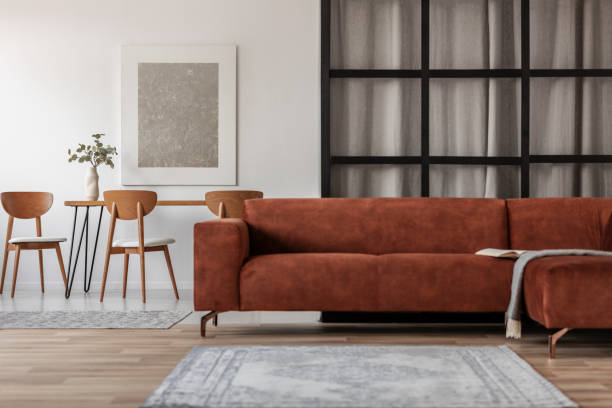 istock Stylish corner sofa in open space studio apartment with dining and living space 1176289317