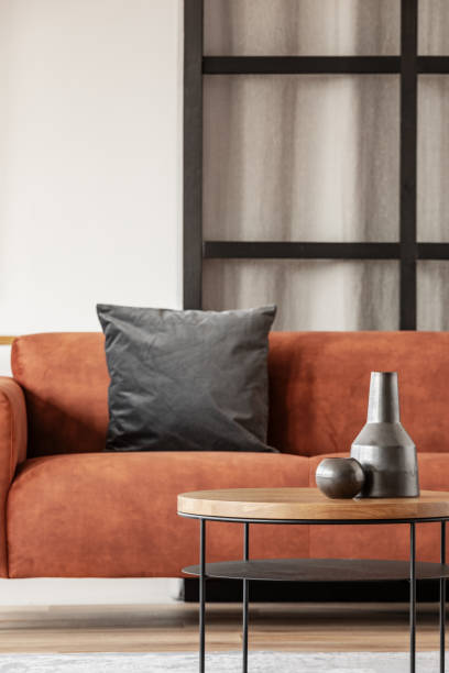 istock Black vase on wooden coffee table in chic living room interior with comfortable sofa 1176289324