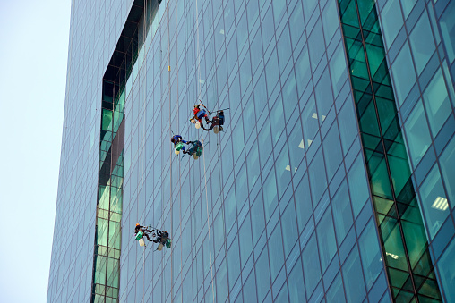 Moscow, Russia - May 28, 2019:  Industrial climbers washes glass on the facade of a skyscraper in the business district called Moscow City