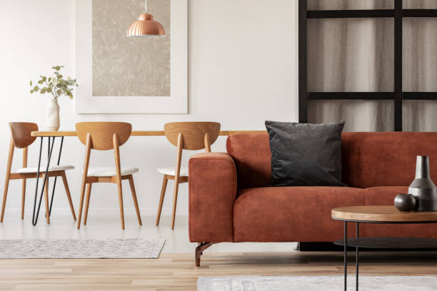 Stylish corner sofa with black pillow in open space studio apartment with dining and living space