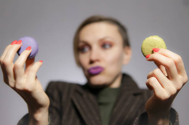 istock Eating macarons. Female hand holding macarons 1176293346