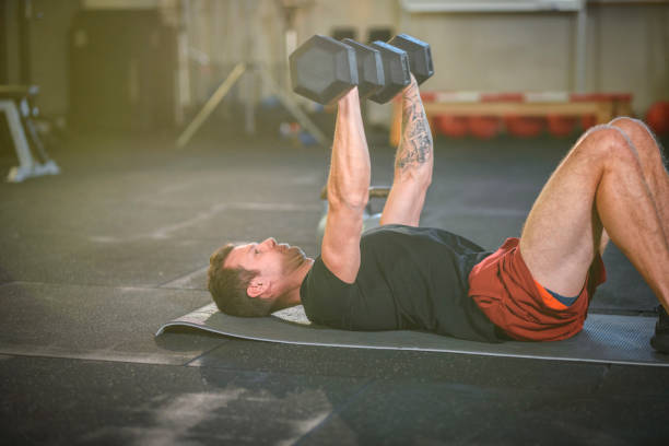 istock Fit Male Athlete Lying on Back and Doing Hex Dumbbell Lifts 1176295977