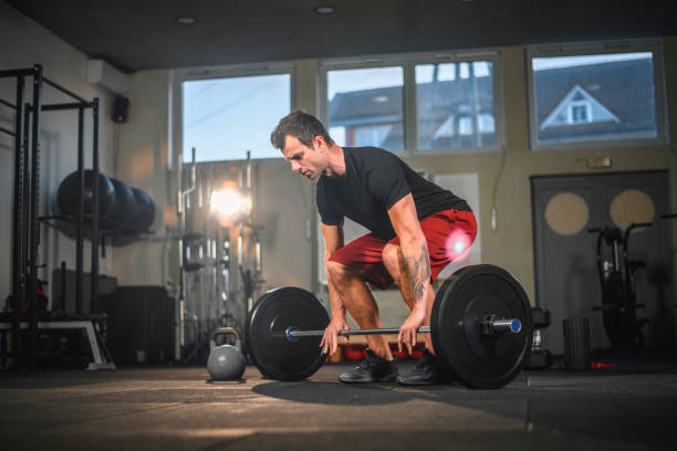 istock Focused Male Athlete Preparing to Lift Barbell with Weights 1176295979