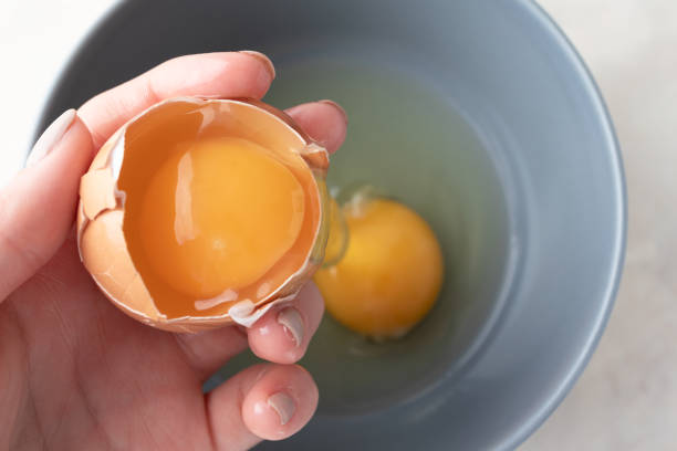 istock Broken organic egg in female hand, top view. Going to make an omelet from chicken eggs, farm product. Breakfast cooking concept 1176298882