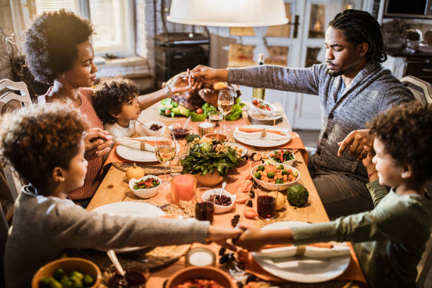 família preta religiosa que diz a benevolência antes do almoço do thanksgiving em casa. - family thanksgiving dinner praying - fotografias e filmes do acervo