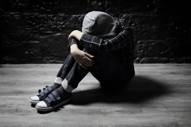 Lonely bullied child with depression sitting on floor