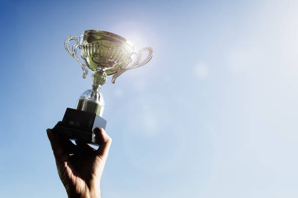 vencedor que sustenta um primeiro lugar que ostenta o copo do troféu - gold medal fotos - fotografias e filmes do acervo