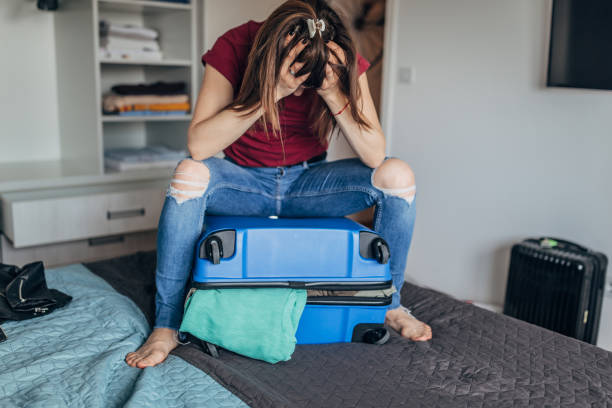 istock Stressed woman sitting on full suitcase 1176304396
