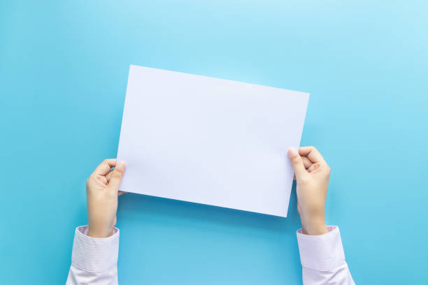 istock close up hands holding  empty white blank letter paper for flyer , presentation or invitation mock up isolated on a blue background. 1176304606