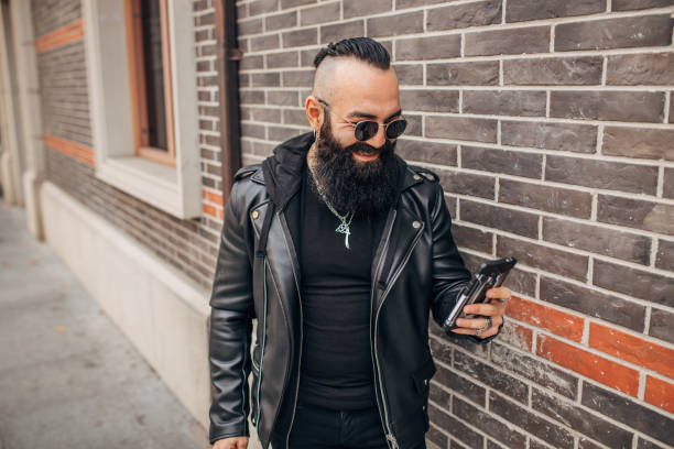 istock Man with beard in black clothing text messaging 1176305940