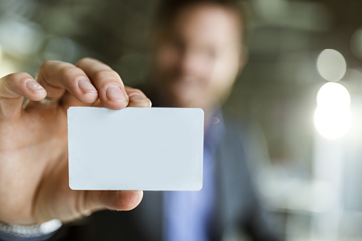 Business man in suit, holding in hand yellow Paper card for text. Copy space