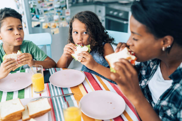 mère et enfants mangeant des sandwichs - healthy lifestyle people eating sister photos et images de collection