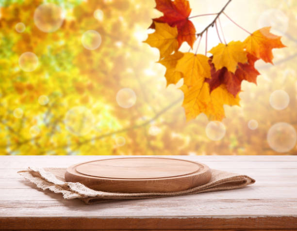 Pizza board with tableclothe on wooden desk. Autumn background. Top view mock up. Selective focus.