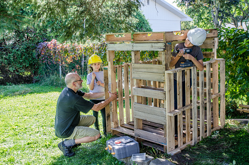Boy and girl building a hut from wooden pallets during summer day
Under the supervision of the father
