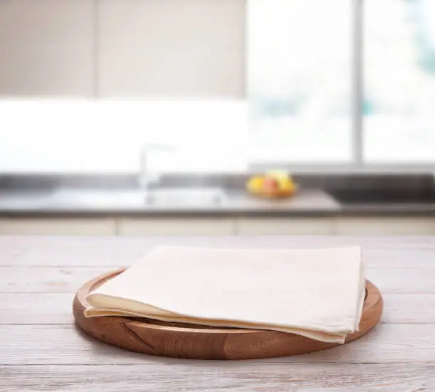 Photo of Empty pizza board with tablecloth on the table and kitchen interior background