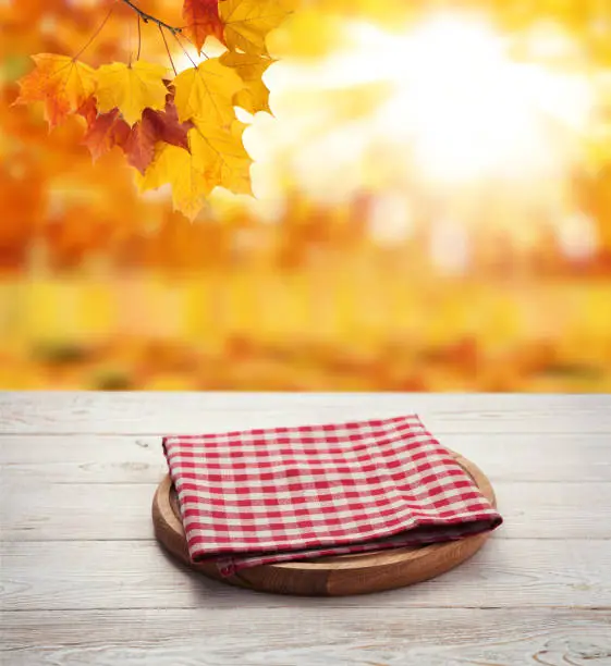 Photo of Napkin. Stack of colorful dish towels on wooden table and autumn background. Top view mock up