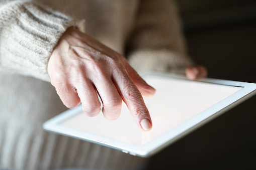 Top view mockup image of a mature woman holding black tablet pc with blank white desktop screen