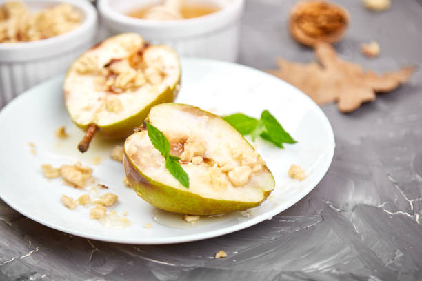 istock Tasty roast pears with honey and walnuts on white plates on grey background table. 1176318333