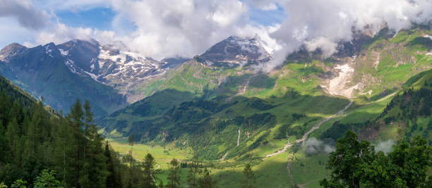 istock Green valleys, high firs and snow-covered mountains in clouds, Austria 1176324287