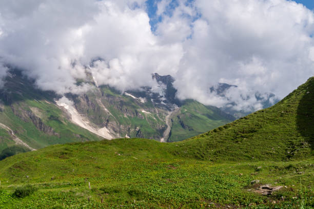 istock Green mountain valley and snowy mountainsides in the clouds, Austria 1176324350