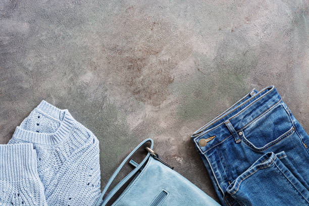istock Blue denim jeans, a blue knitted sweater and a leather blue bag on a dark rustic background. Flat lay female autumn and winter clothes. Stylish female outfit. Top view. 1176326437