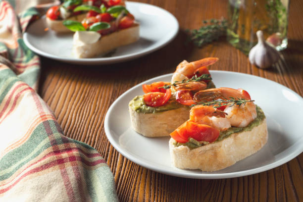 bruschetta with shrimp, basil pesto sauce and mozzarella on a white plate on a wooden background. Italian restaurant. Top view food photo stock photo