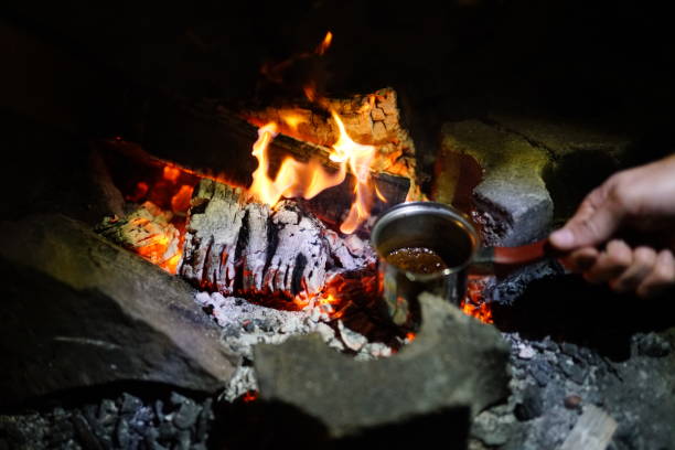 Boiling coffee in turkish cezva on campfire coals. Luxury camping concept.