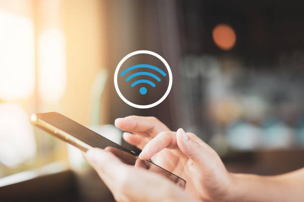 mujer mano usando el teléfono inteligente con el icono wifi fondo abstracto en la cafetería con luz bokeh de colores. - wireless technology fotografías e imágenes de stock