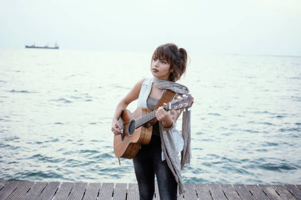 Cute young girl with guitar waving long hair in modern room