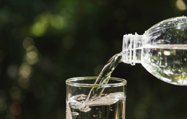 istock Pouring water from bottle into the glass on blurred background. 1176335265