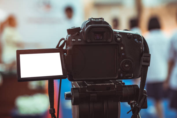istock Photo Video or professional digital dslr with blank lcd on tripod for camera recording taking photograph in production house or convention hall in live streaming event, media meeting  broadcast equipment. 1176339229