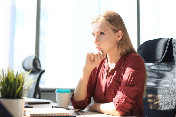 istock Concentrated modern woman is keeping hand on chin and thinking about business while working in the office 1176340643