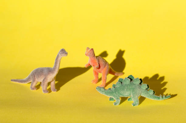 istock Colored toy dinosaurs (Brachiosaurus, Stegosaurus, Tyrannosaurus) on yellow background. 1176347198