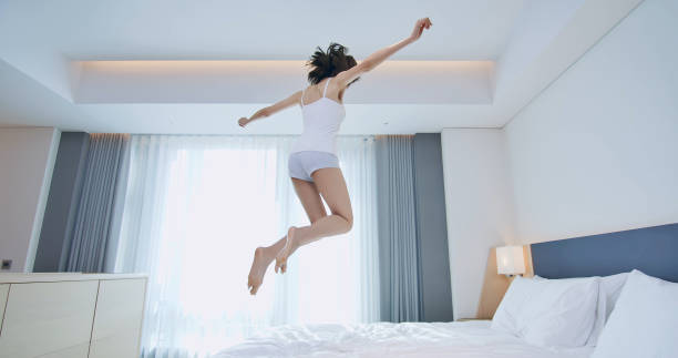 istock Young woman jump on bed 1176349899