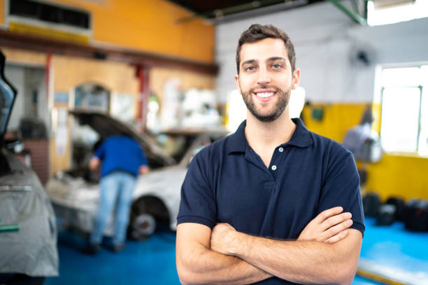 hombres de pie en un taller de reparación de automóviles con los brazos cruzados - customer auto repair shop car mechanic fotografías e imágenes de stock
