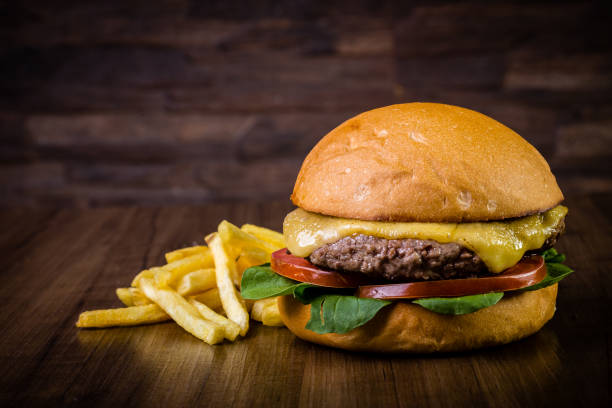 istock Craft beef burger with cheese, rocket leafs and french fries on wood table and rustic background 1176359522