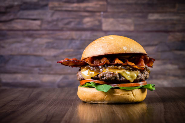 istock Craft beef burger with cheese, bacon, caramelized onion and rocket leafs on wood table and rustic background 1176361551