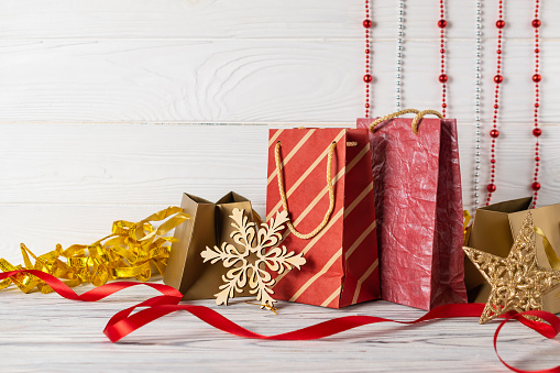 Christmas shopping sale composition with red paper bags and decorations on white wooden table