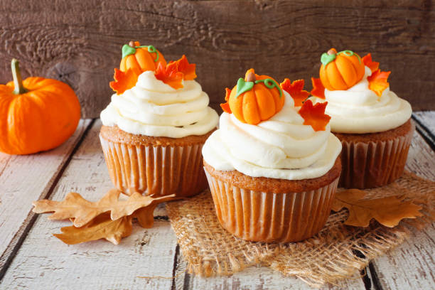 istock Fall pumpkin spice cupcakes with creamy frosting close up against rustic wood 1176362437