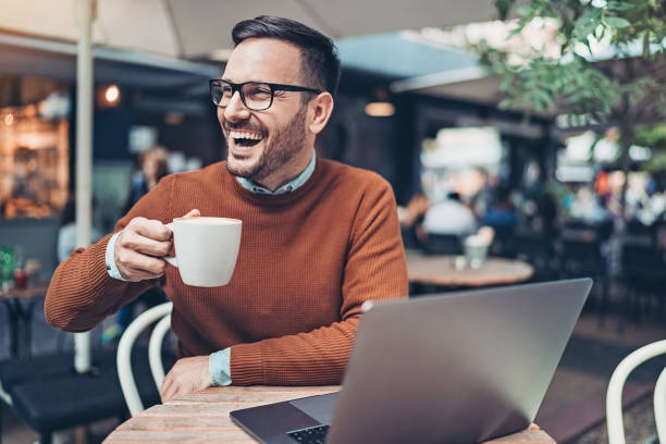 улыбающийся бизнесмен пьет кофе и использует ноутбук - cafe laptop espresso business стоковые фото и изображения