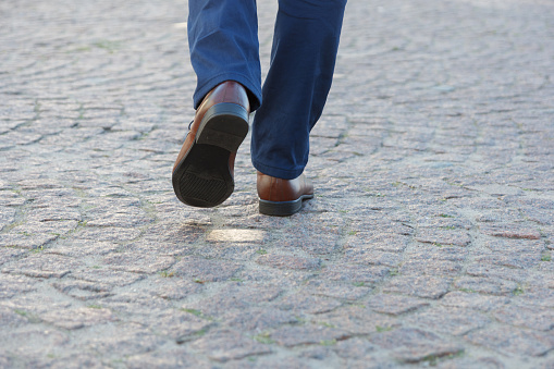 Close up legs of businessman walking in modern city