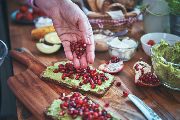 подготовка авокадо сэндвич с коричневым хлебом и гранатом - brown bread bread home interior food стоковые фото и изображения