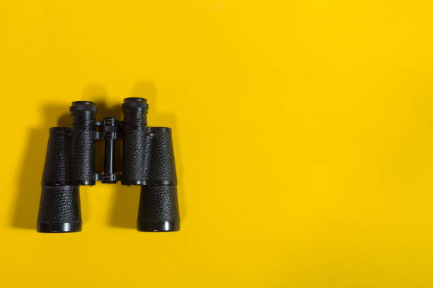 Binoculars on yellow background Black metalic binoculars on a yellow background binoculars photos stock pictures, royalty-free photos & images