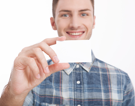 Young man holding blank form close-up on white background. Handsome man holding and showing a blank sheet of paper. White blank billboard close-up on white background. Mock up.