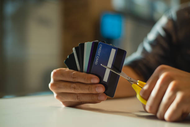 joven cortando tarjeta de crédito con tijeras, el hombre está destruyendo tarjetas de crédito debido a una gran deuda. - cortar fotografías e imágenes de stock