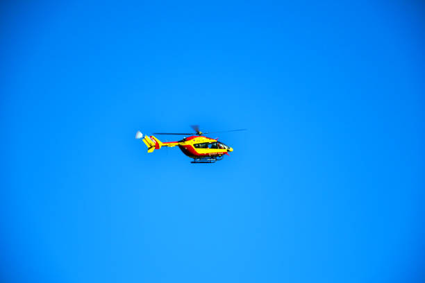 Helicopter in flight against blue sky. Modern rescue technology hovering with new engine. Pilot maneuvers small aircraft showcasing speed and rescue capabilities.
