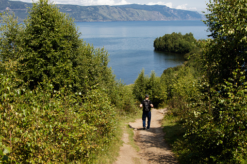 A tourist walking along the path leading to the Shaman Peninsula. Lake Baikal near the city of Slyudyanka, Irkutsk region, Russia.